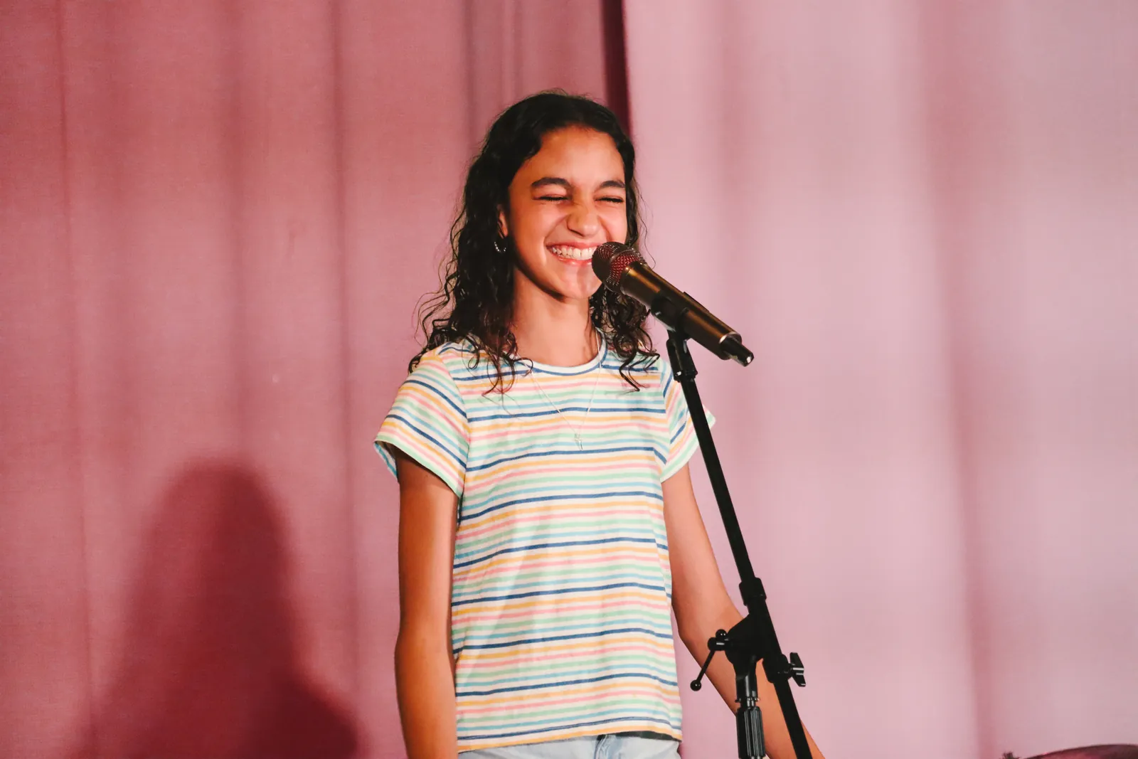 A CBY Academy student singing into a microphone on stage