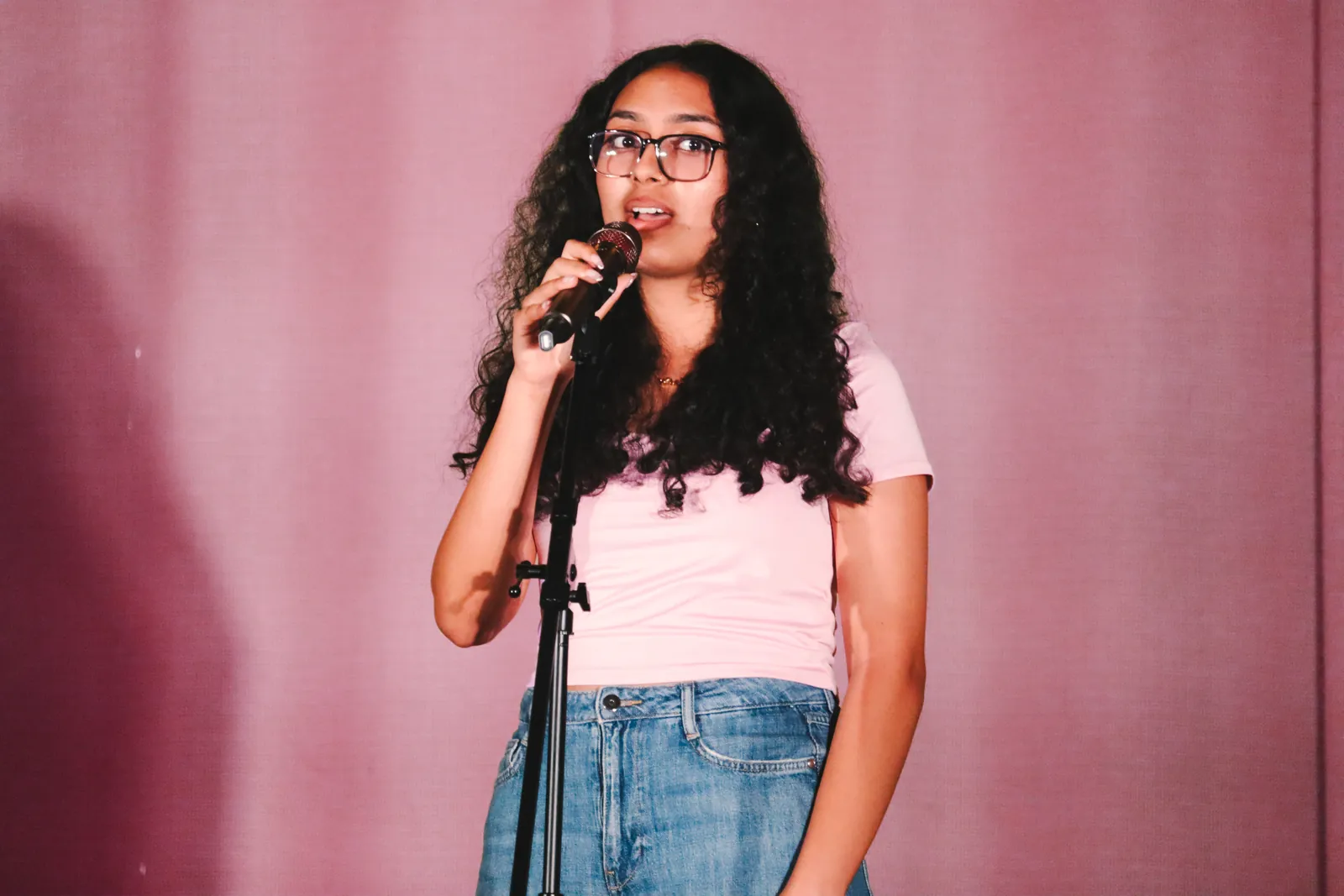 A CBY Academy student singing into a microphone on stage